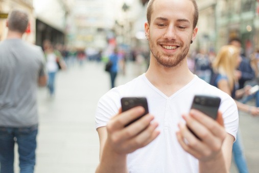 Создать мем: человек с телефоном в руке, счастливый парень, чел с двумя телефонами