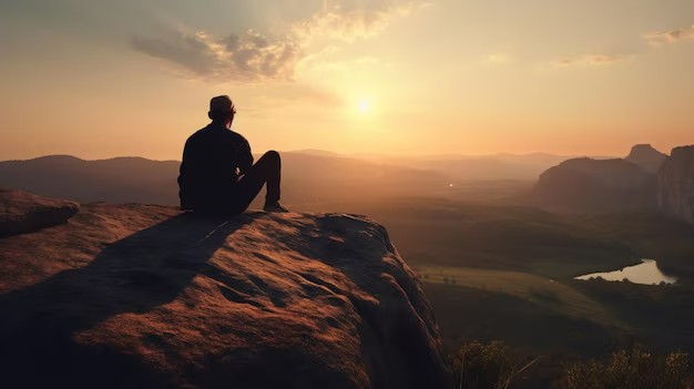 Создать мем: человек сидит на закате, мужчина на скале, рассвет в горах
